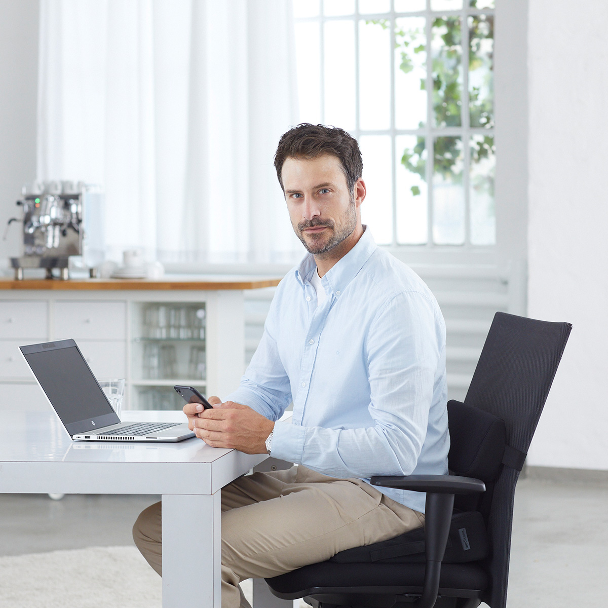Man using a heated seat cushion in the office for enhanced comfort and warmth while working at a desk